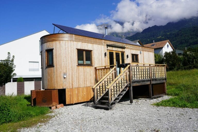 Tiny Home in a wooden design, with curved ends; solar panels are mounted on the roof