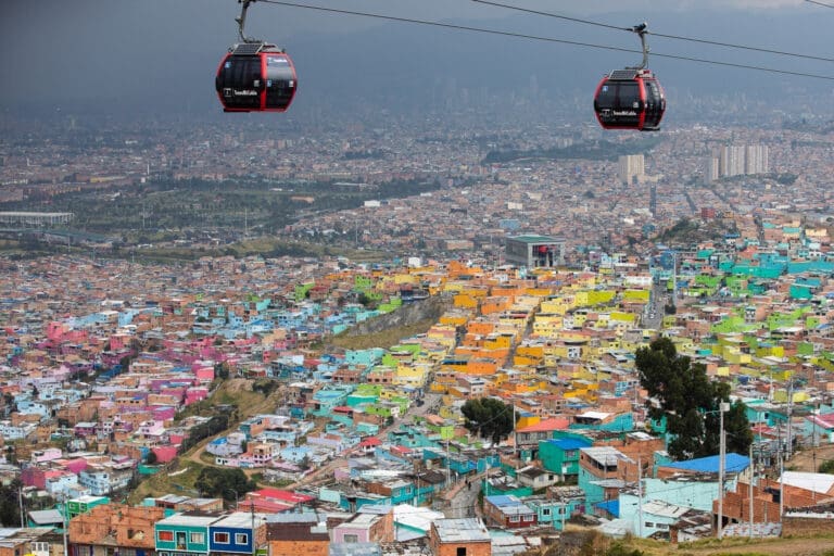 Two cable cars running high above a vast valley with colorful suburbs in the southeast of Bogota