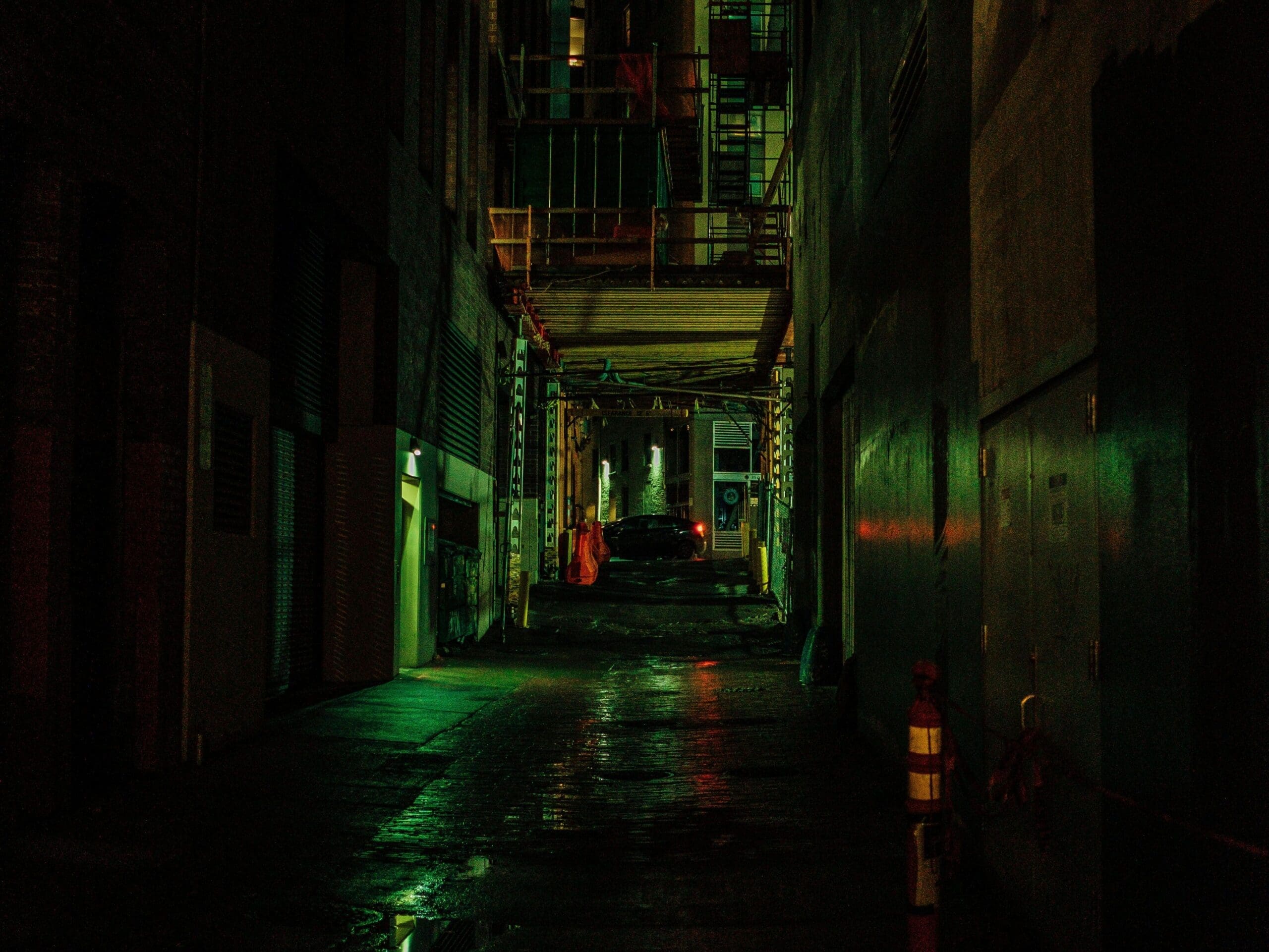 Gloomy wet lane between high-rise buildings at night; views like that often used in dystopian movies