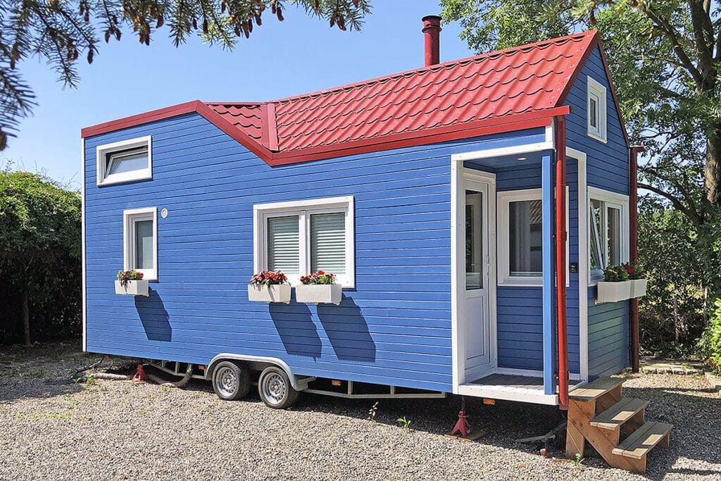 Colorful red and blue tiny house on a trailer; a sustainable pellet oven serves as heating source