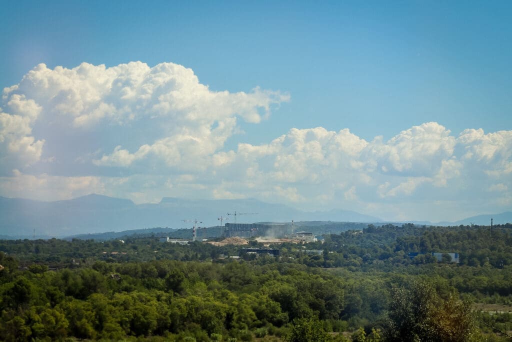 Baustelle der ITER-Fusionsanlage inmitten eines Waldes, mit einer Bergkette im Hintergrund