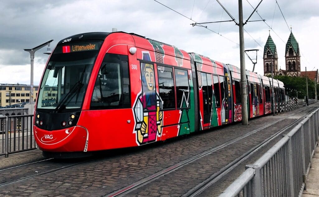 Eine rote Straßenbahn fährt in einen Vorort außerhalb der Freiburger Altstadt