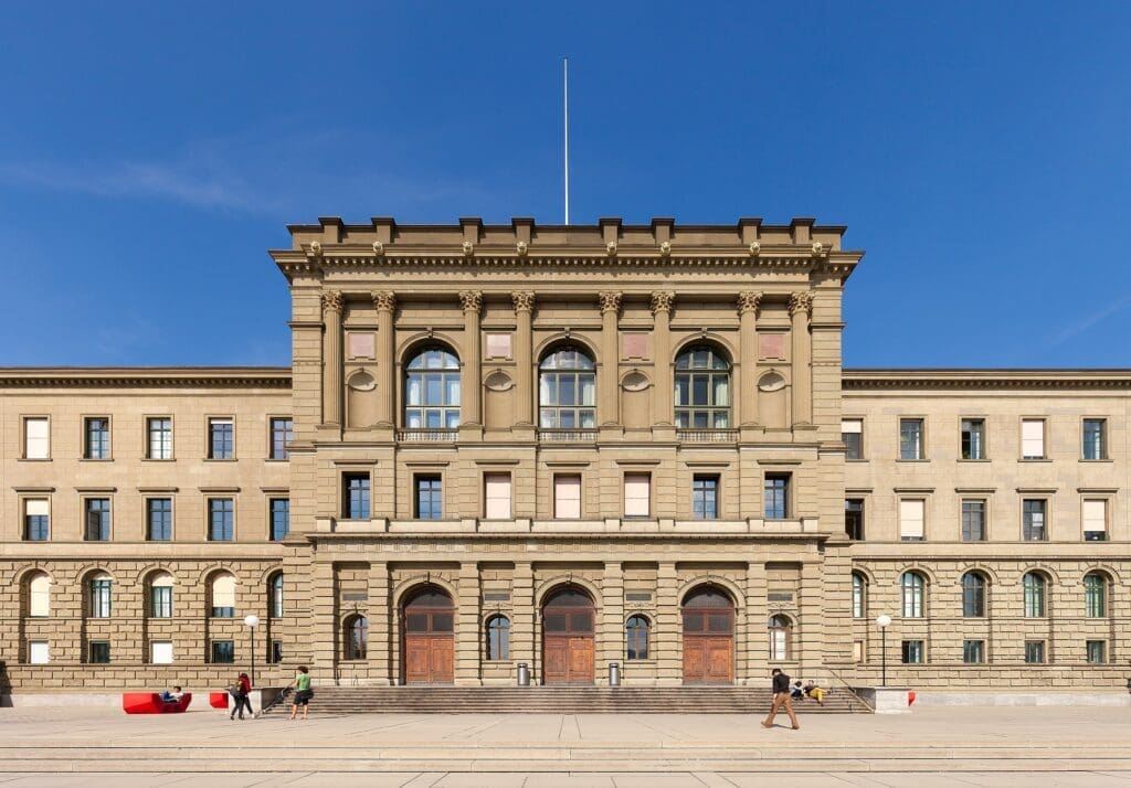 Die beigefarbene Fassade der ETH Zürich im neoklassizistischen Stil. Das kühne Design des Gebäudes spiegelt Gottfried Sempers Vision wider, einen "Tempel der Wissenschaft" zu schaffen.