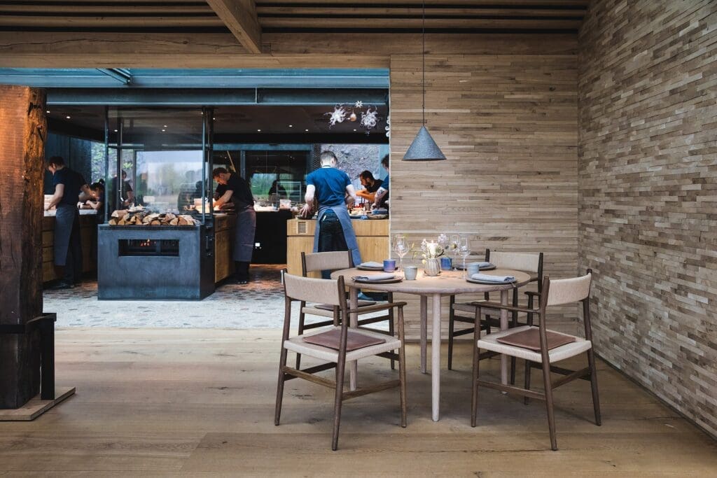 At Michelin-starred Noma in Copenhagen, a beautifully set table sits in the foreground while the open kitchen and service staff animate the background