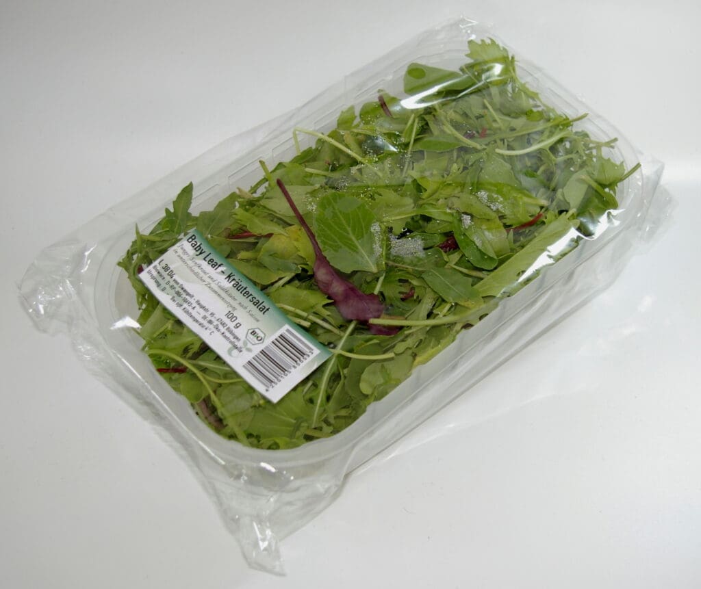 Transparente Blisterverpackung für einen grünen Salatbehälter