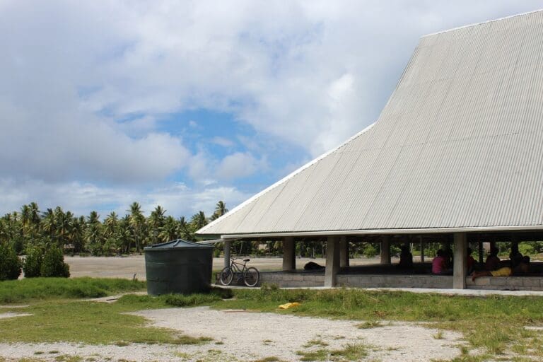 Large white building roof with one corner connected to a water tank for collecting rainwater