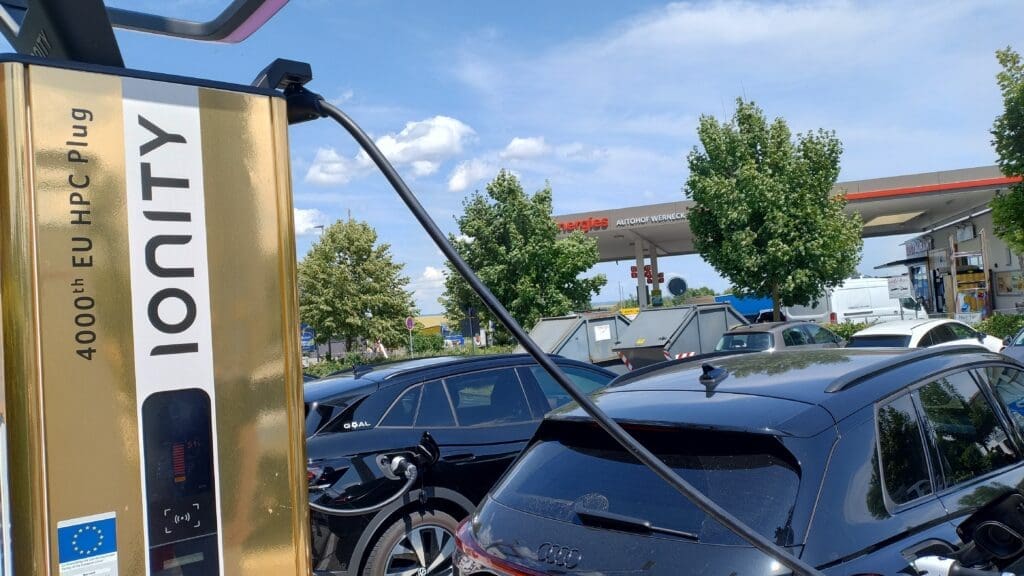 Golden 4000th Ionity fast charger at a service area, connected to a black SUV EV