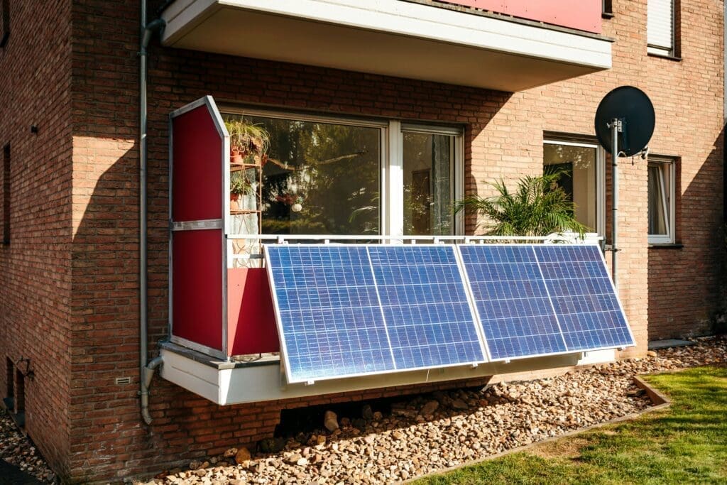 Solar panels mounted on a residential balcony of a brick apartment building, demonstrating a compact balcony solar installation for home energy generation