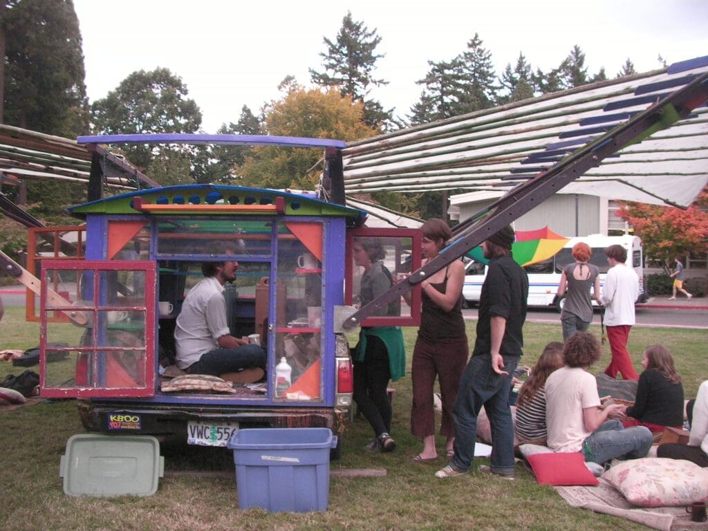 People gathering around a colorful city repair "T-horse" mobile, touring local parks and public spaces